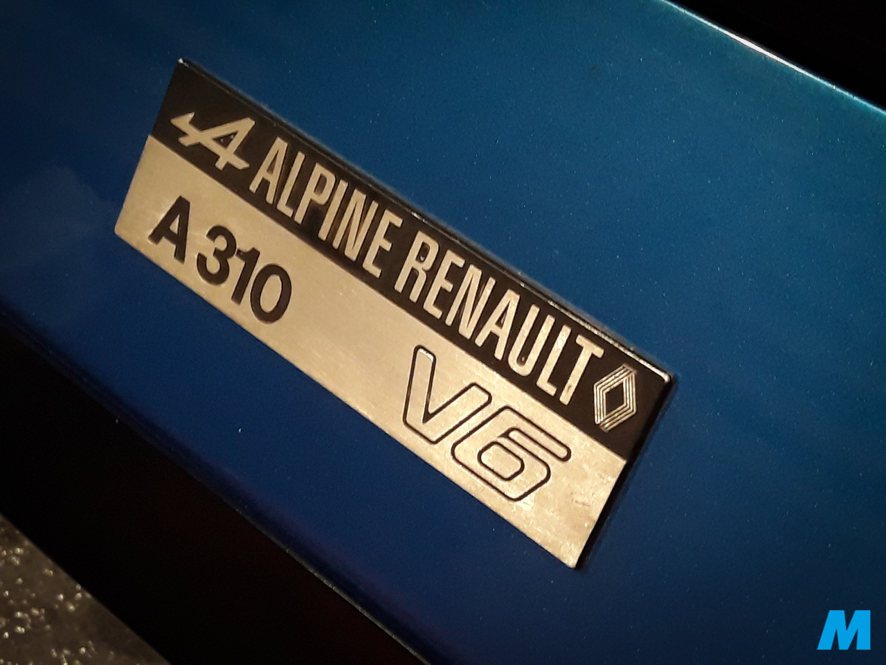 Plaque « Alpine Renault A310 V6 » sur la carrosserie bleue d'une Alpine exposée à Epoqu'Auto 2018