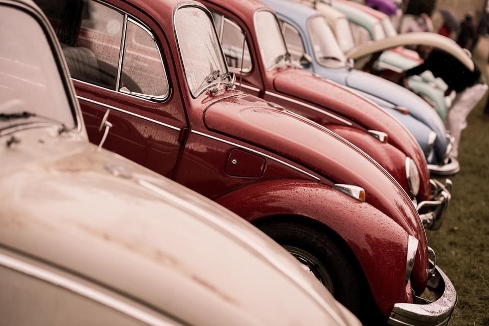 Ailes avant de Volkswagen Coccinelle rouge, blanche et bleue alignées dans l'herbe lors de la VW Castle Party 2020