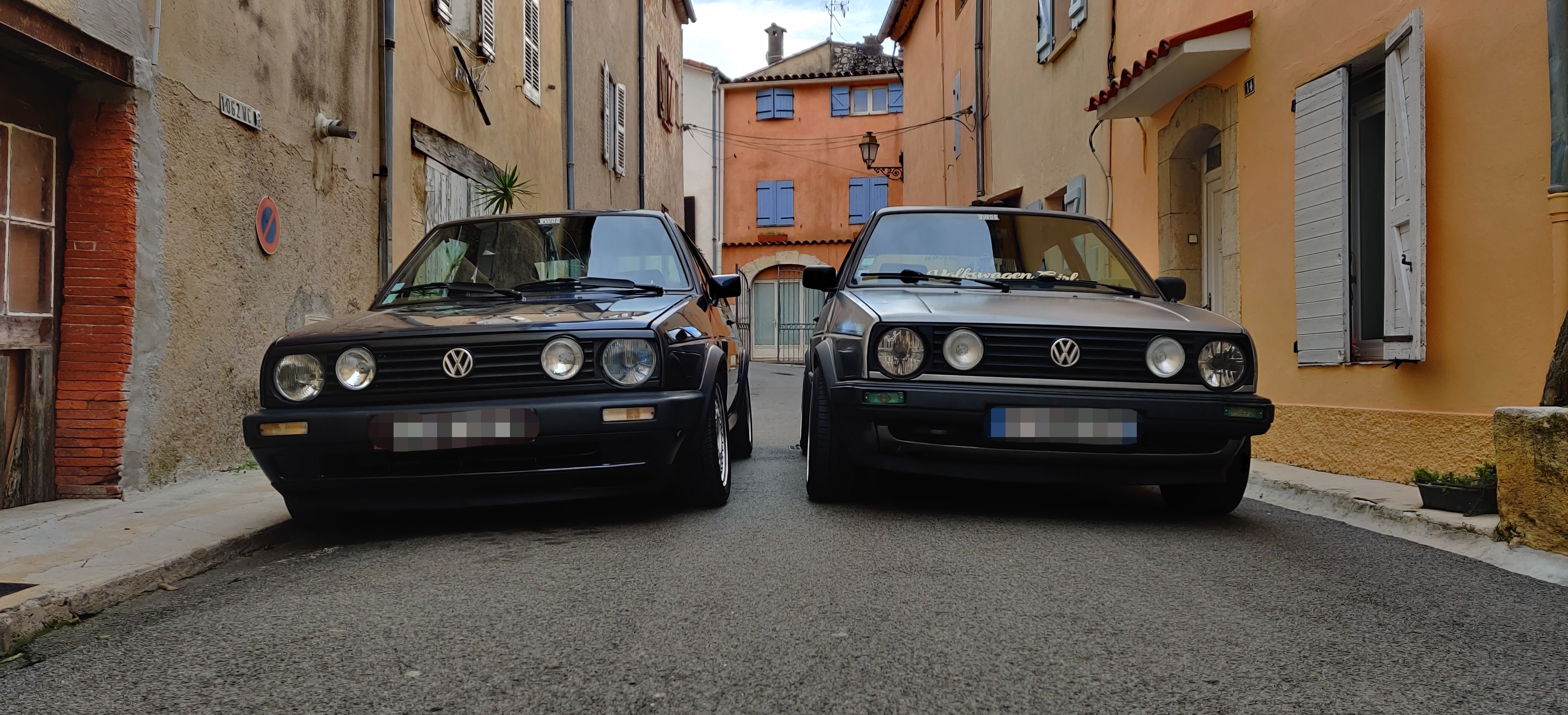 Deux Volkswagen Golf 2 garées face à face dans une ruelle, plaques floutées