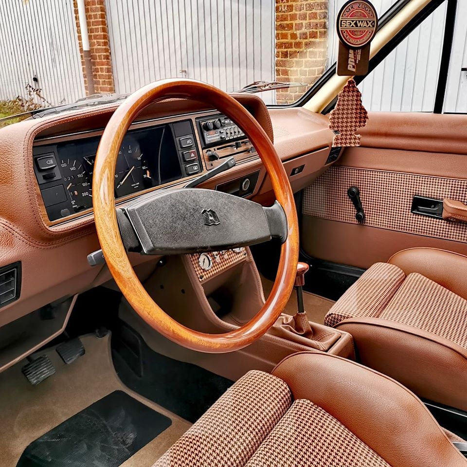 Habitacle restauré d'une Passat B1 : volant en bois, planche de bord et sièges en simili cuir brun et tissu pied-de-poule